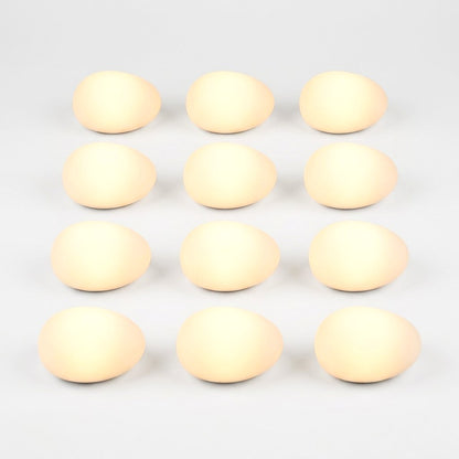Twelve frosted solar glass pebble lights glowing warm yellow in a grid of three by four on a light background