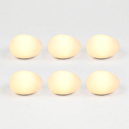 Six frosted solar glass pebble lights glowing warm yellow in a grid of three by two on a light background
