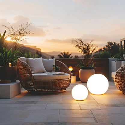 Outdoor patio with wicker furniture, spherical lights, and plants during sunset.