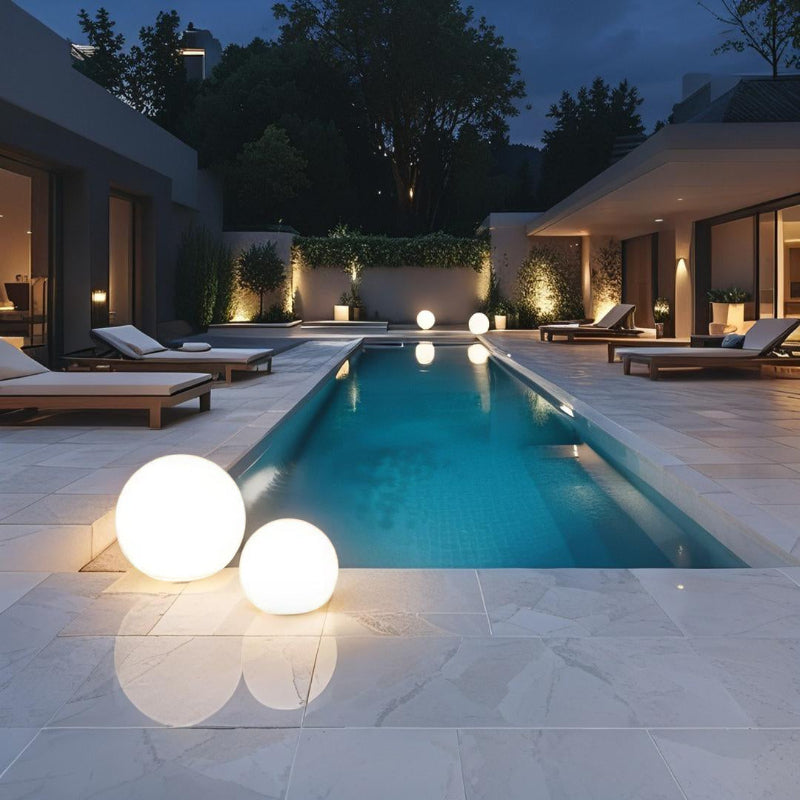 Modern pool area with lounge chairs and illuminated spheres at night