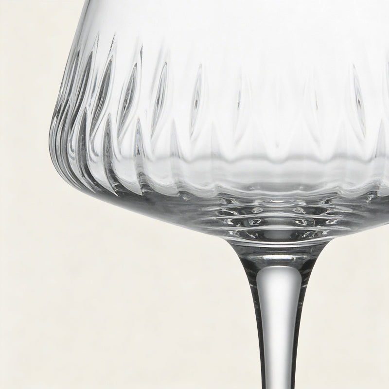 Close-up of a clear glass with textured bowl on a light beige background