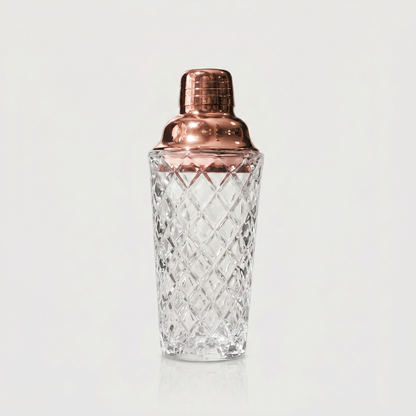 Glass cocktail shaker with rose gold lid on white background