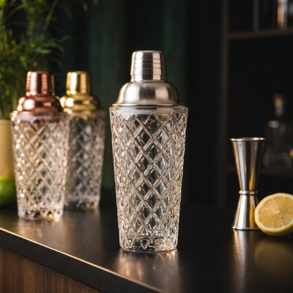 Glass cocktail shaker with copper lid beside lemons and jigger