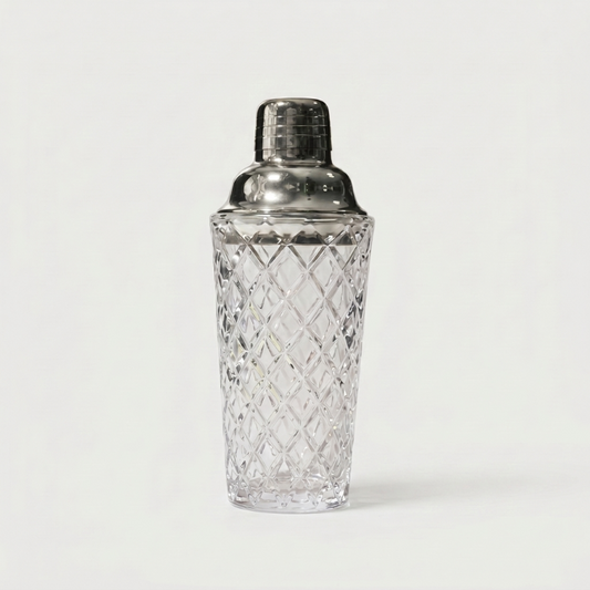 Glass cocktail shaker with silver lid on white background