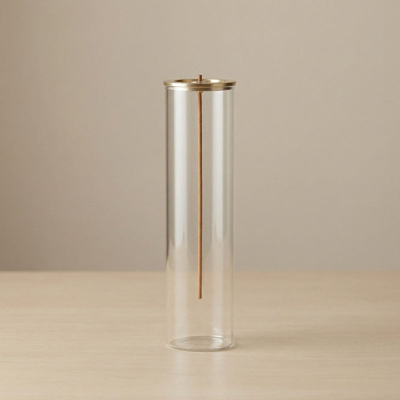 Cylindrical glass vase with gold accent on a beige background