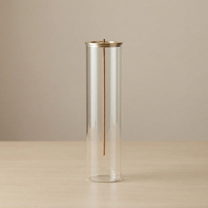 Cylindrical glass vase with gold accent on a beige background