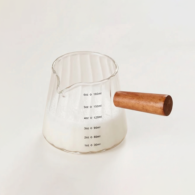 Glass milk frothing pitcher on white background