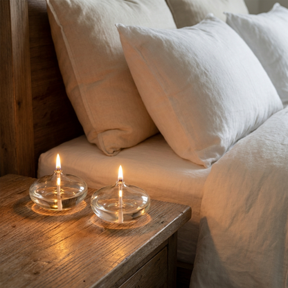 Glass oil candles on bedside table in soft neutral bedroom