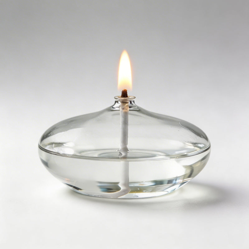 Clear glass oil candle with lit wick