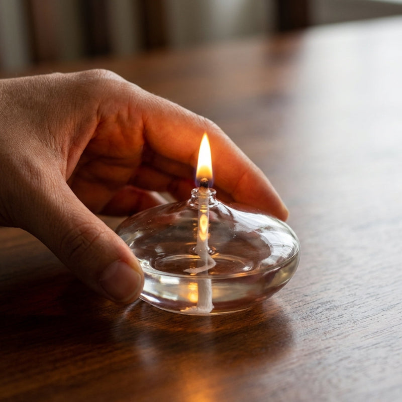 Hand holding clear glass oil candle showing size
