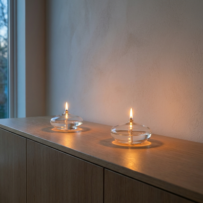 Glass oil candles on windowsill in evening light