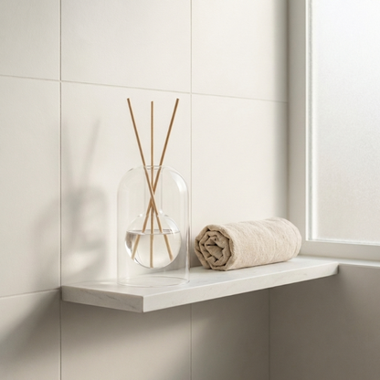 Glass reed diffuser on a bathroom shelf.