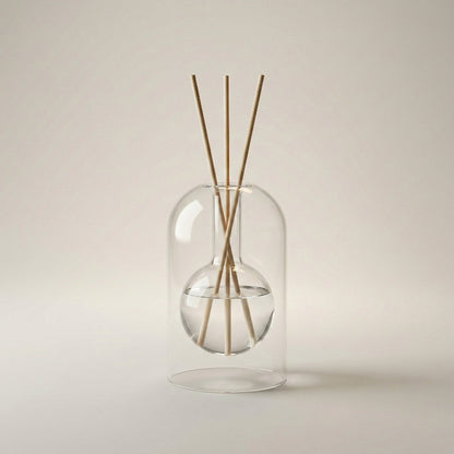 Clear glass diffuser with wooden sticks on a beige background