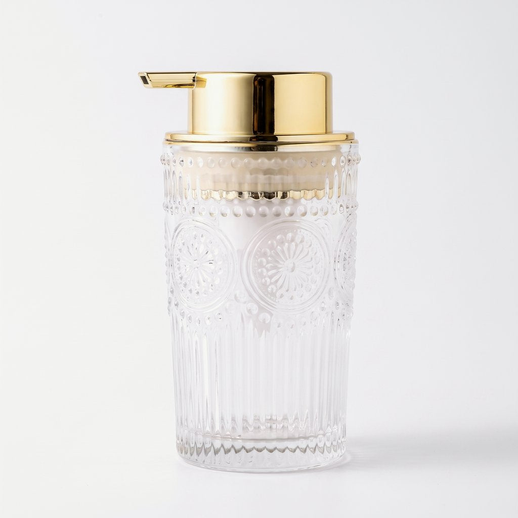 Medium clear embossed glass soap dispenser with a gold pump on a white background