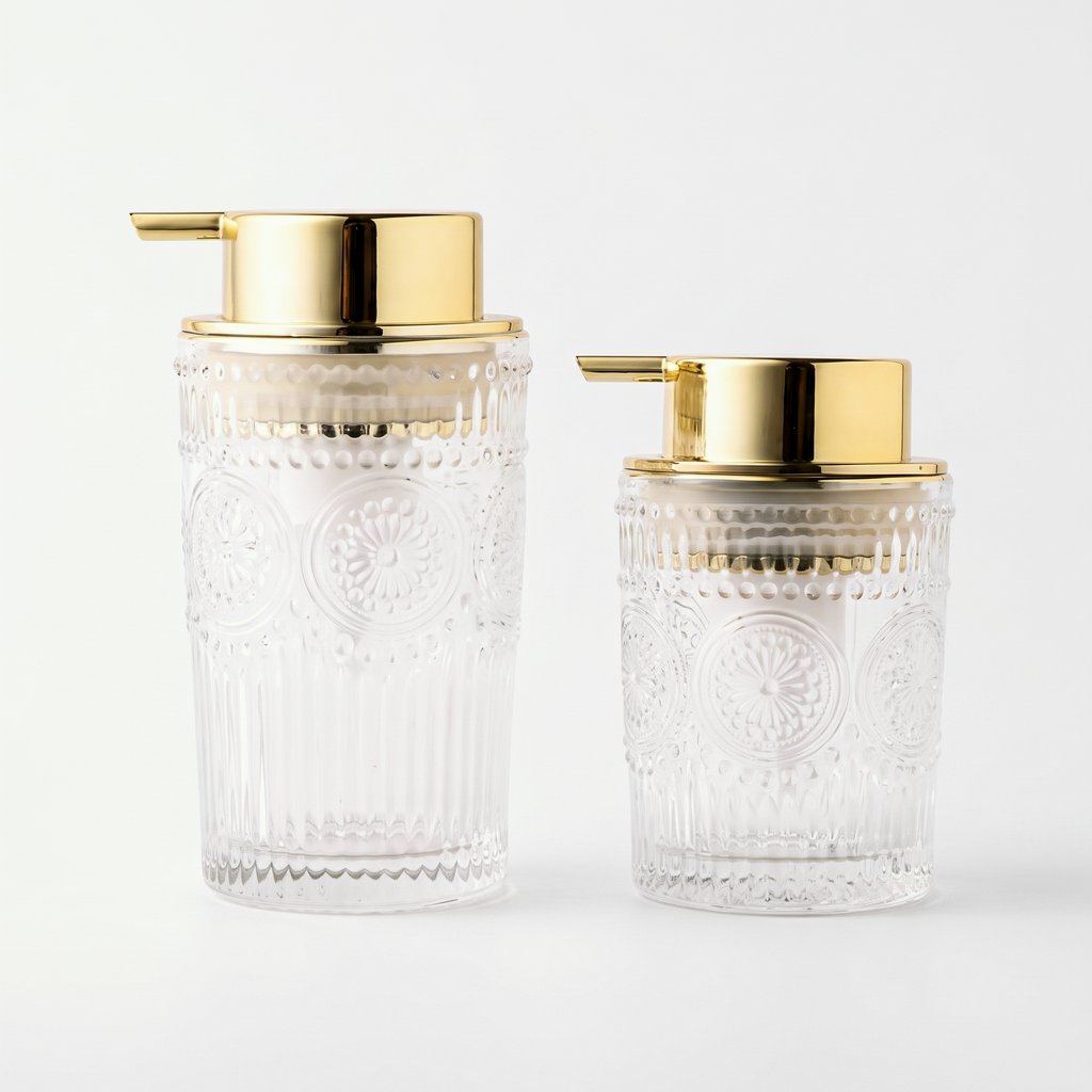 Medium and small clear glass soap dispensers with gold pumps side by side on a light background