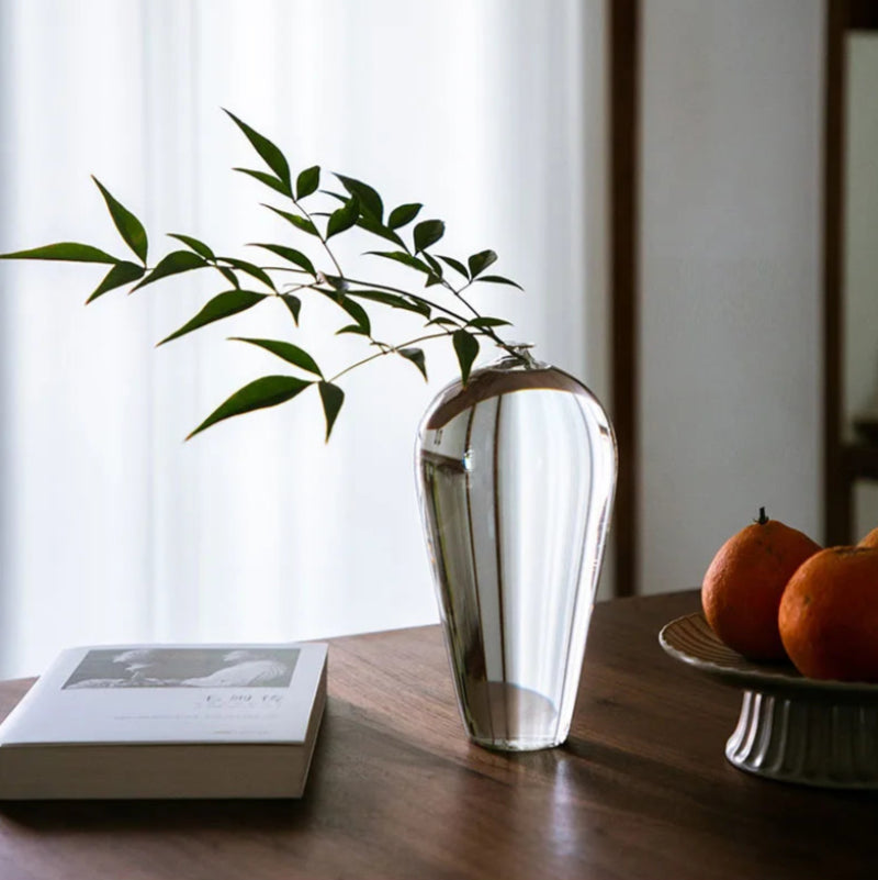 Cylindrical glass vase filled with colorful flowers, placed on a dining table for a modern and inviting centerpiece.