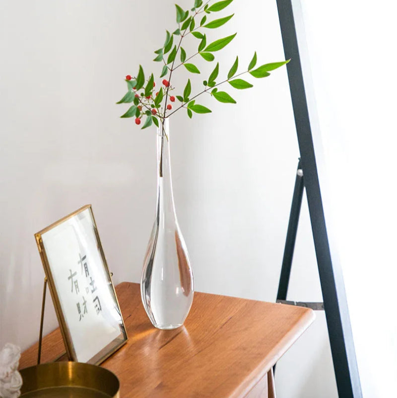 Transparent glass vase with holly, adding a touch of sophistication to a living room corner.