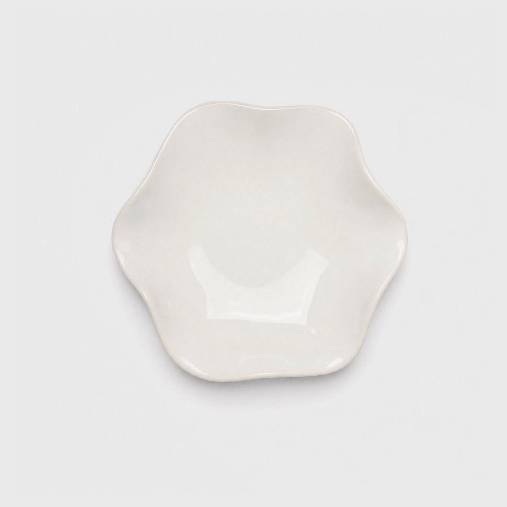 Single glossy ivory glazed ceramic dish with a softly wavy rim and a thin cream edge on a plain light gray background