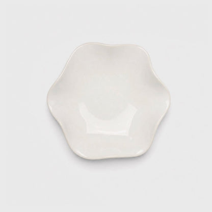 Single glossy ivory glazed ceramic dish with a softly wavy rim and a thin cream edge on a plain light gray background