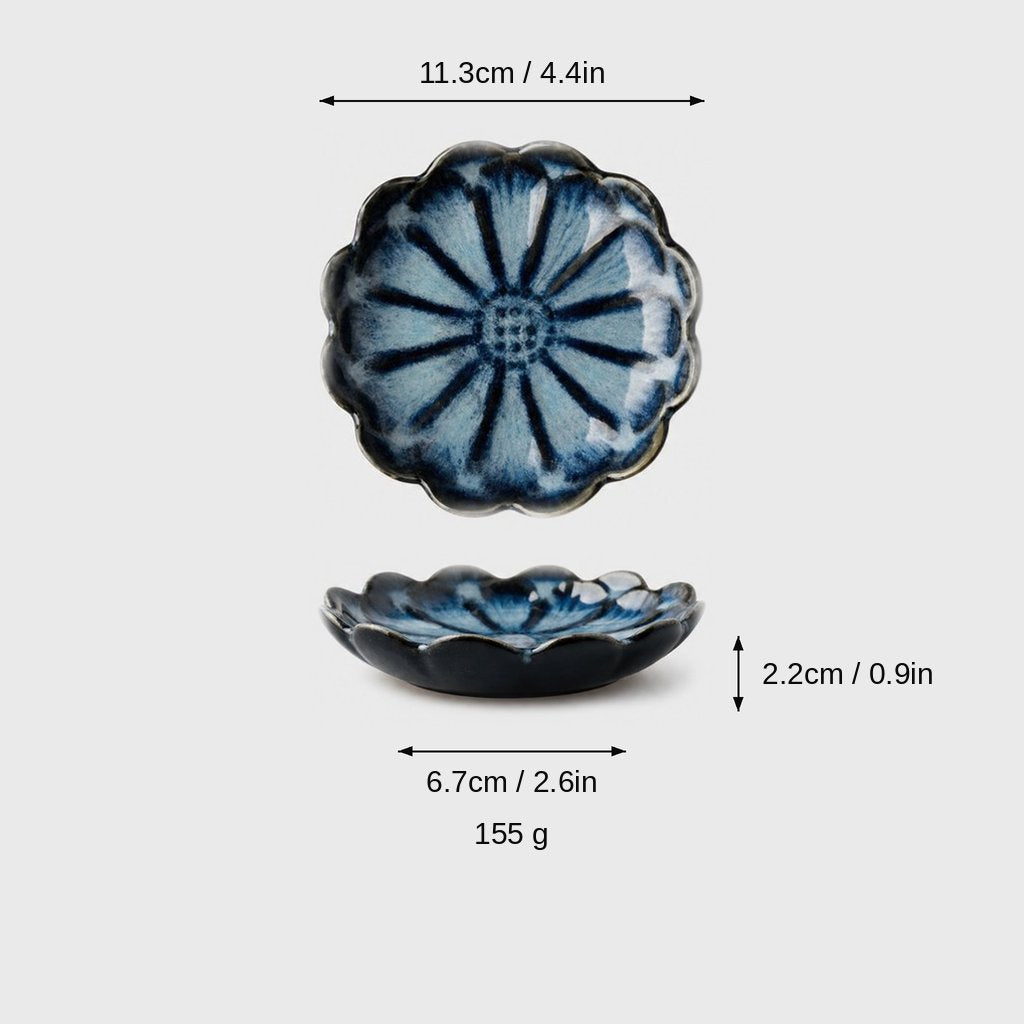 Dimensions graphic of a navy glazed scalloped ceramic dish with light blue petals in top and side views, labeled 11.3cm / 4.4in wide, 2.2cm / 0.9in high, 6.7cm / 2.6in base and 155 g