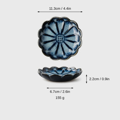 Dimensions graphic of a navy glazed scalloped ceramic dish with light blue petals in top and side views, labeled 11.3cm / 4.4in wide, 2.2cm / 0.9in high, 6.7cm / 2.6in base and 155 g