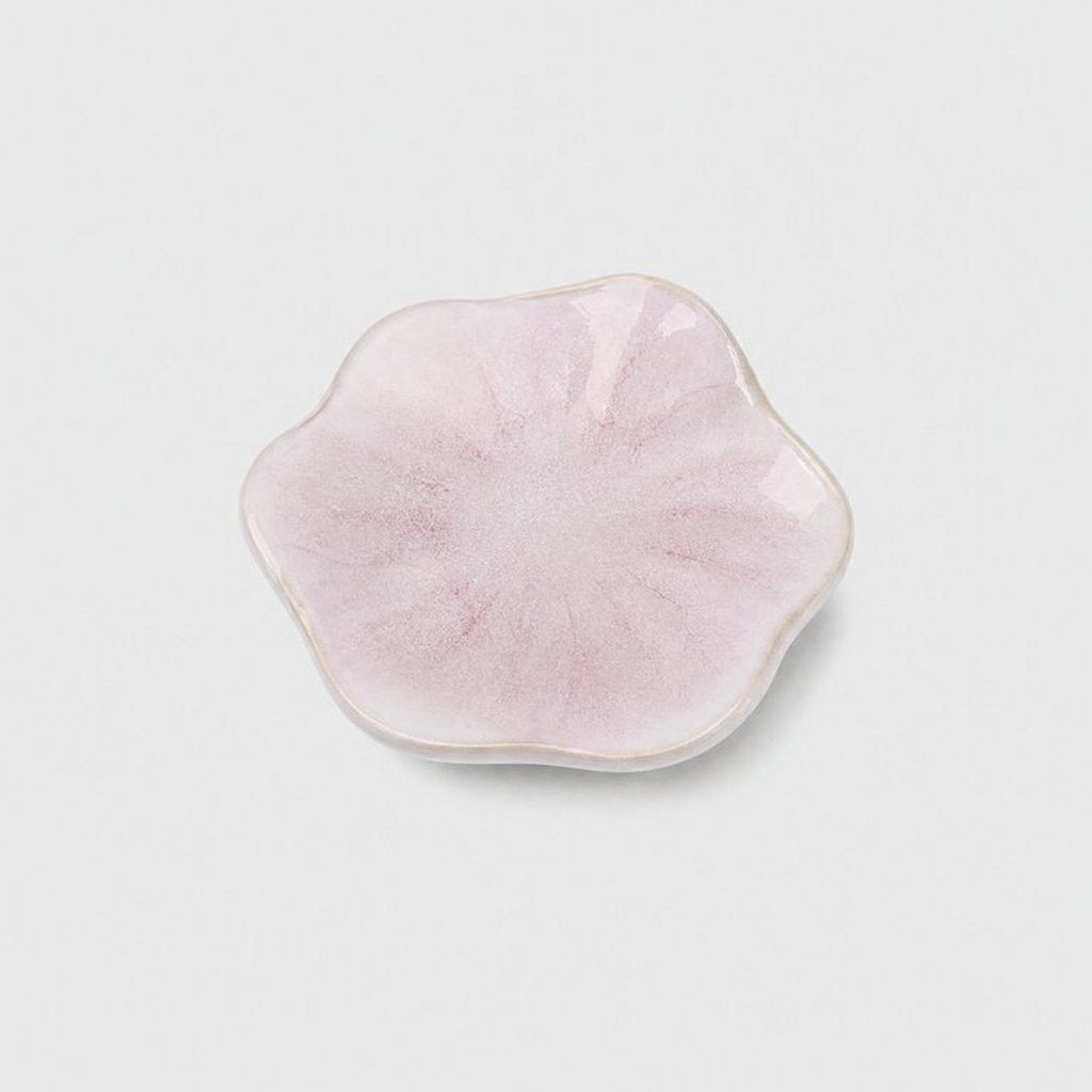 Single glossy pale pink glazed ceramic dish with a wavy flower-shaped rim and rose-pink streaks on a plain light gray background