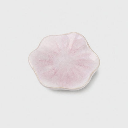 Single glossy pale pink glazed ceramic dish with a wavy flower-shaped rim and rose-pink streaks on a plain light gray background