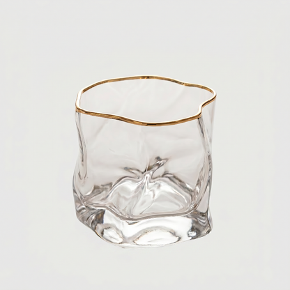 Clear glass with gold rim on a light gray background