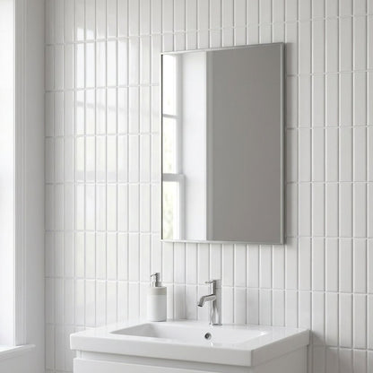 White glossy subway tile wall in a bathroom behind a mirror and vanity sink