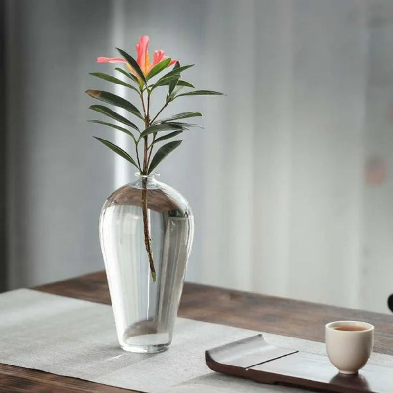 Glass vase on coffee table with cup of tea.