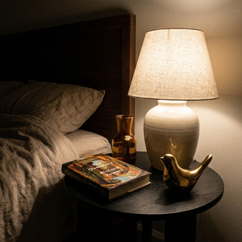 Gold bird sculpture on bedside table with lamp and books