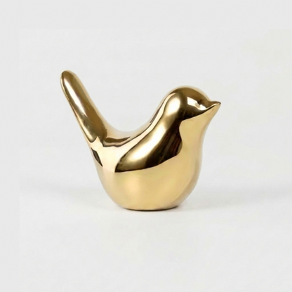 Gold bird sculpture on white background facing left