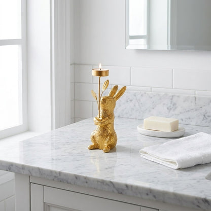 Gold standing rabbit candle holder on a marble vanity with soap and towel