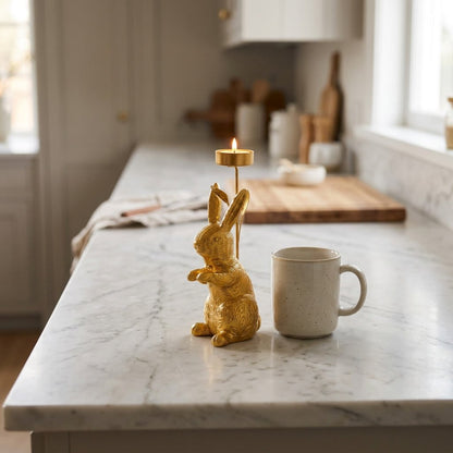 Gold standing rabbit candle holder on a kitchen counter next to a mug