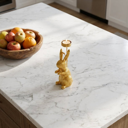 Gold standing rabbit candle holder on marble kitchen island beside fruit bowl