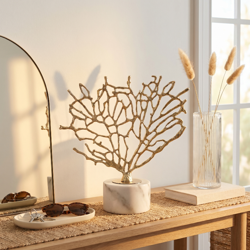 Gold coral sculpture in dark green vase on desk beside lamp and notebook
