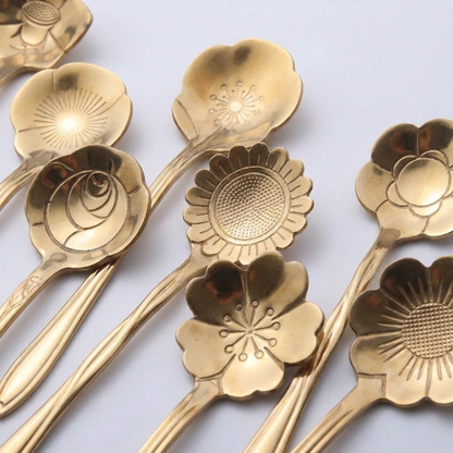 Set of gold floral-patterned spoons on a light gray background