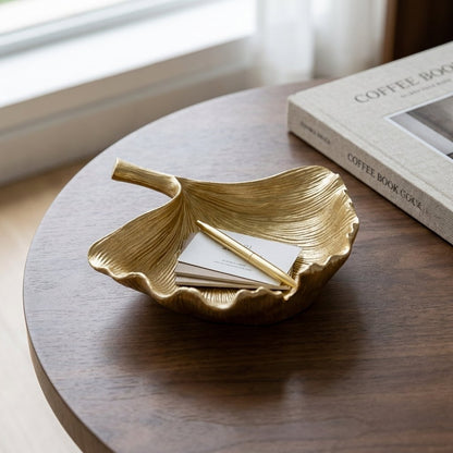 Gold ginkgo leaf tray holding business cards and a pen on a coffee table