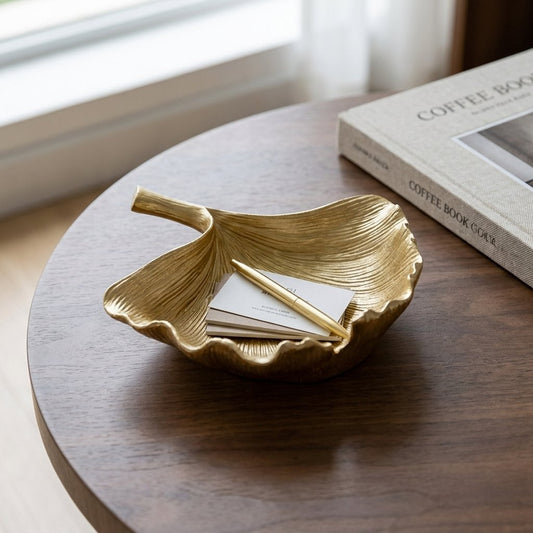 Gold ginkgo leaf tray holding business cards and a pen on a coffee table