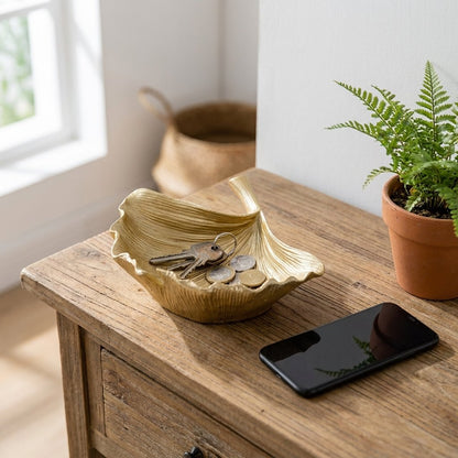 Gold ginkgo leaf tray holding keys and coins on an entryway console table