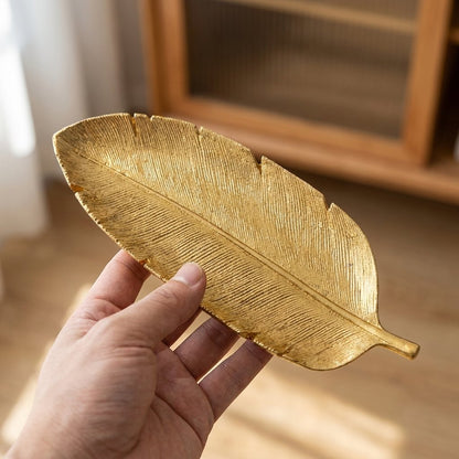 Gold leaf tray held in a hand showing its etched leaf-vein texture and size