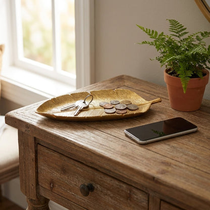 Gold leaf tray with keys and coins on a wood entryway console table