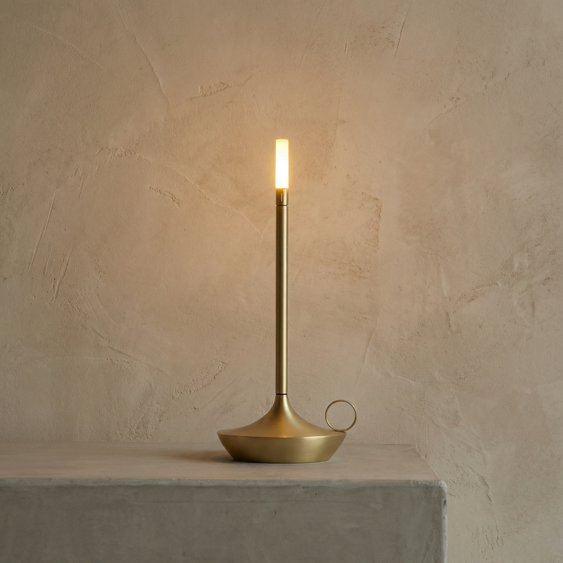 Gold table lamp on a concrete surface with a beige wall background