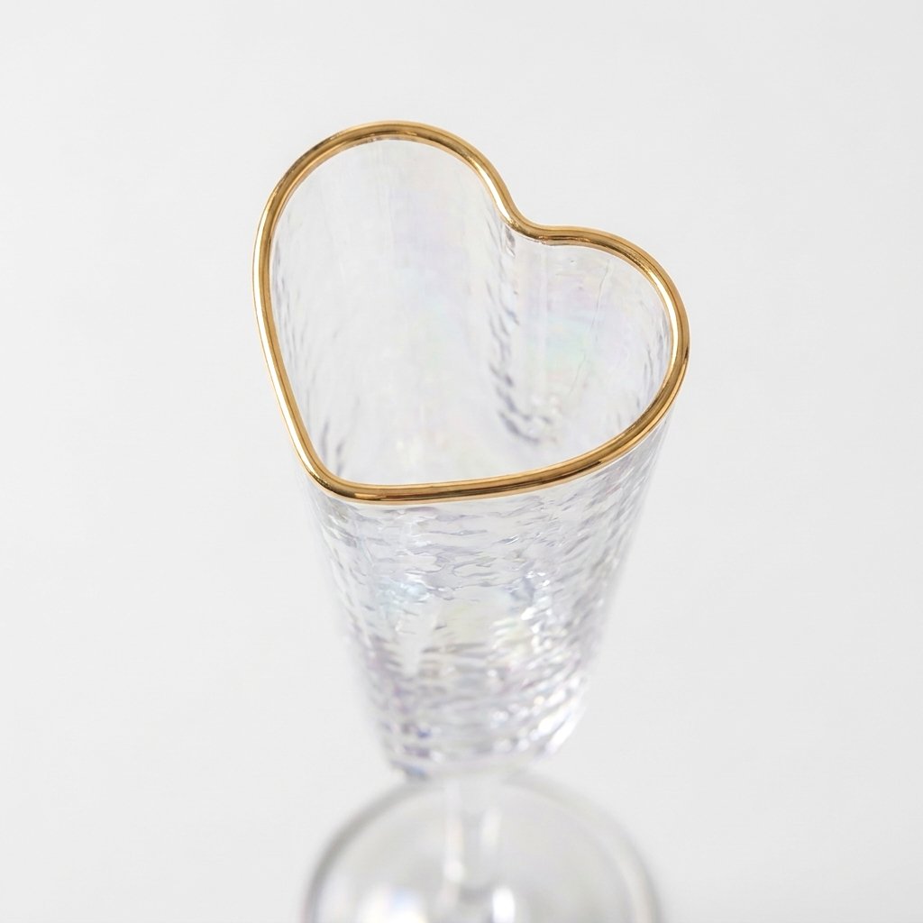 Close-up of a heart-shaped champagne flute rim traced in gold with hammered glass texture