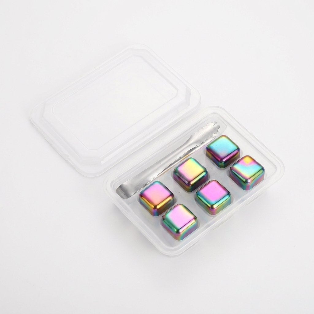 Six iridescent rainbow chilling stones in a clear tray with silver tongs on a white background
