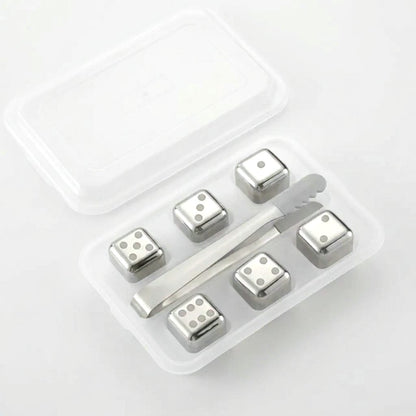 Six silver dice-style chilling stones with dot faces in a clear tray with silver tongs on a white background