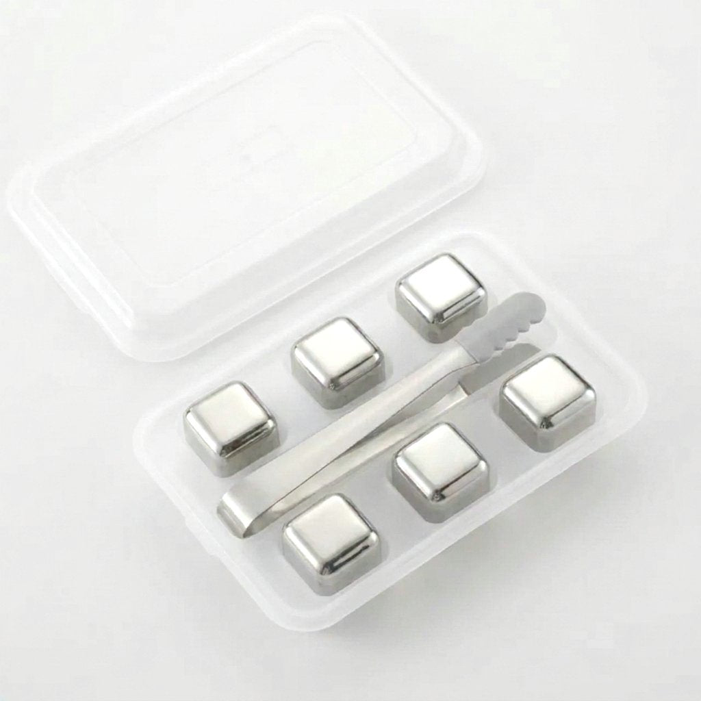 Six plain silver chilling stones in a clear tray with silver tongs on a white background