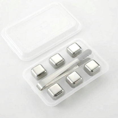 Six plain silver chilling stones in a clear tray with silver tongs on a white background