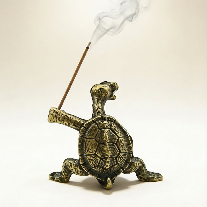 Bronze turtle incense burner with a smoking incense stick on a beige background