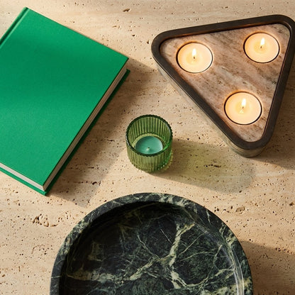 Empty green marble pedestal fruit bowl shown from overhead beside a book and lit candles